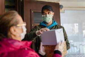 masked man delivering package during coronavirus pandemic