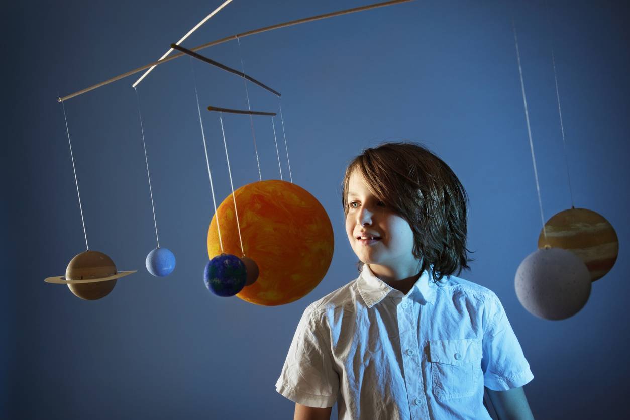 A child standing next to a solar system model