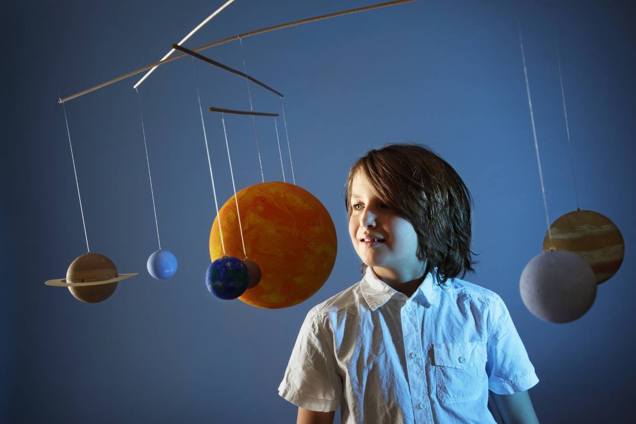 A child standing next to a solar system model